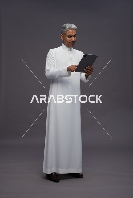 رجل سعودي يتفاعل مع جهاز لوحي بالزي التقليدي