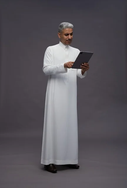 رجل سعودي يتفاعل مع جهاز لوحي بالزي التقليدي