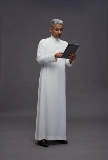 رجل سعودي يتفاعل مع جهاز لوحي بالزي التقليدي