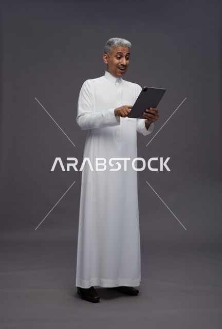 رجل سعودي يتفاعل مع جهاز لوحي بالزي التقليدي