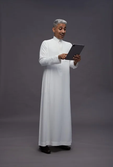 رجل سعودي يتفاعل مع جهاز لوحي بالزي التقليدي