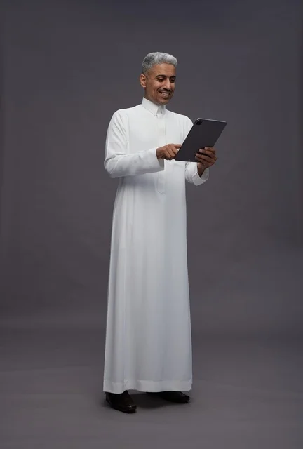 رجل سعودي يتفاعل مع جهاز لوحي بالزي التقليدي
