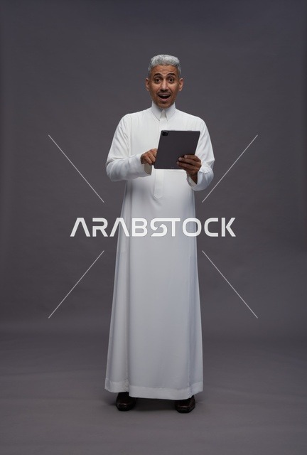 رجل سعودي يتفاعل مع جهاز لوحي بالزي التقليدي