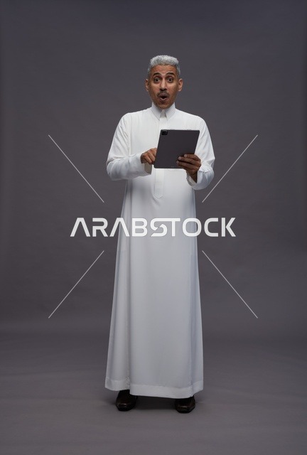 رجل سعودي يتفاعل مع جهاز لوحي بالزي التقليدي