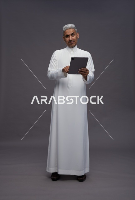 رجل سعودي يتفاعل مع جهاز لوحي بالزي التقليدي