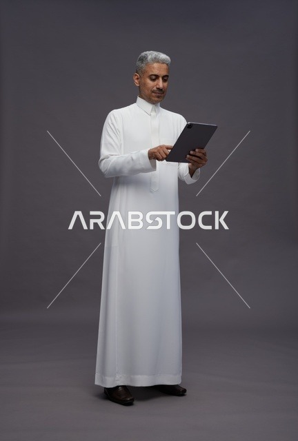 رجل سعودي يتفاعل مع جهاز لوحي بالزي التقليدي