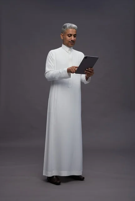 رجل سعودي يتفاعل مع جهاز لوحي بالزي التقليدي