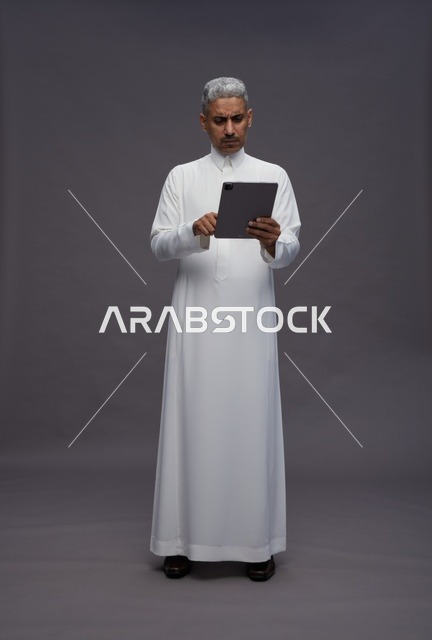 رجل سعودي يتفاعل مع جهاز لوحي بالزي التقليدي