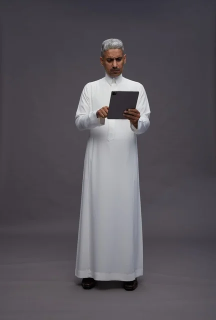 رجل سعودي يتفاعل مع جهاز لوحي بالزي التقليدي