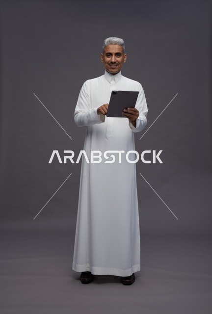 رجل سعودي يتفاعل مع جهاز لوحي بالزي التقليدي