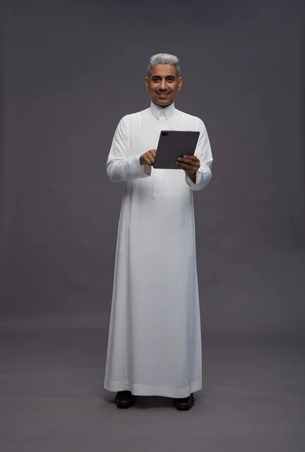رجل سعودي يتفاعل مع جهاز لوحي بالزي التقليدي