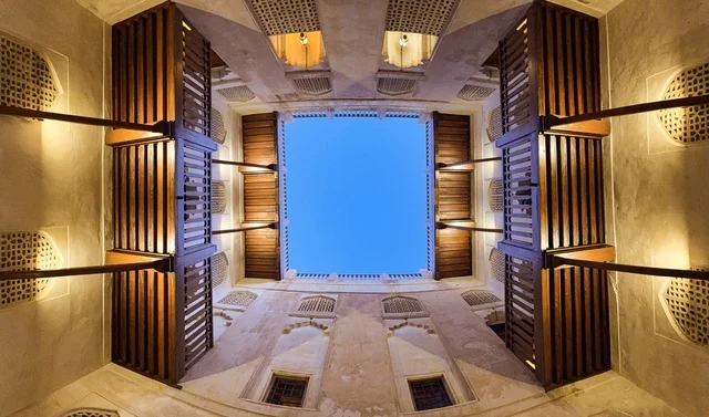 منظر داخلي متناظر في حصن جبرين بسلطنة عمان يظهر العمارة العمانية التقليدية والأقواس الخشبية حول الفناء الداخلي.