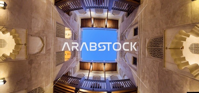 منظر داخلي متناظر في حصن جبرين بسلطنة عمان يظهر العمارة العمانية التقليدية والأقواس الخشبية حول الفناء الداخلي.