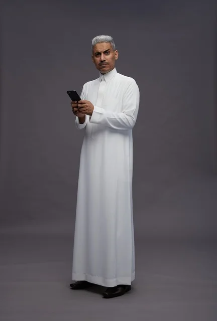 Saudi Man in Traditional Thobe Using Smartphone