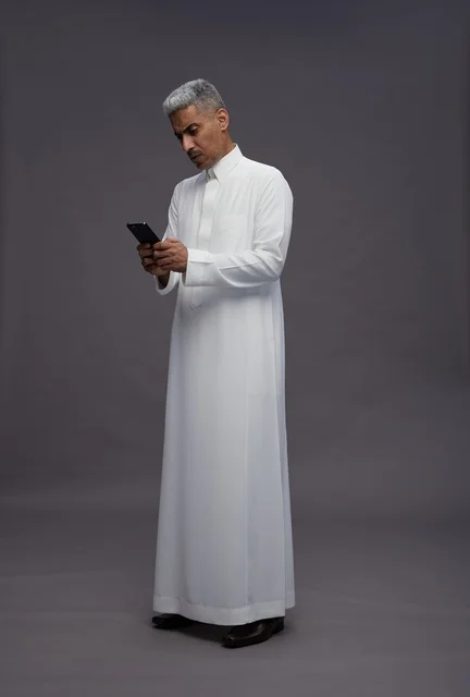 Saudi Man in Traditional Thobe Using Smartphone