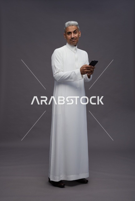 رجل سعودي بالزي التقليدي يستخدم الهاتف الذكي