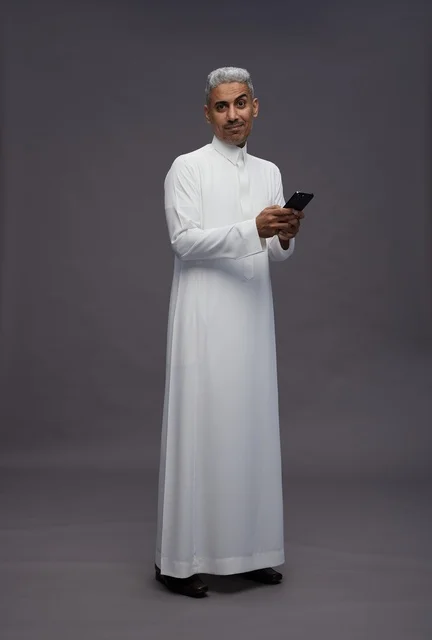 رجل سعودي بالزي التقليدي يستخدم الهاتف الذكي