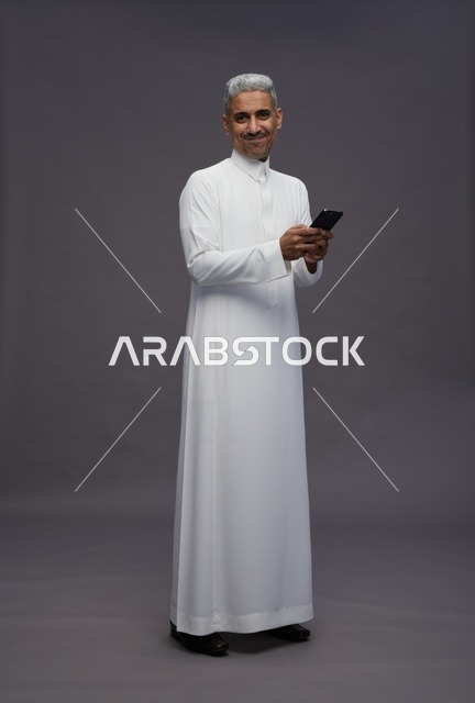 رجل سعودي بالزي التقليدي يستخدم الهاتف الذكي