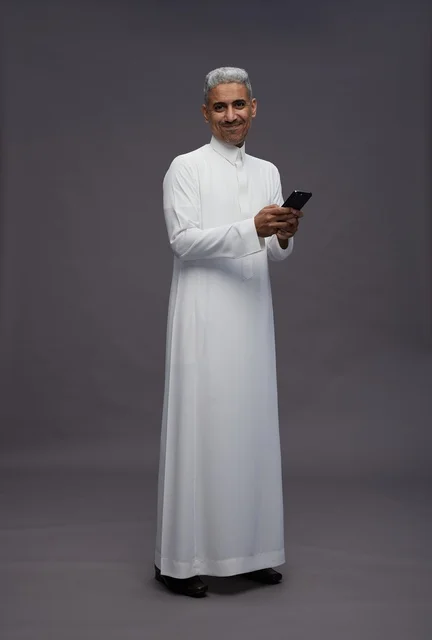 رجل سعودي بالزي التقليدي يستخدم الهاتف الذكي