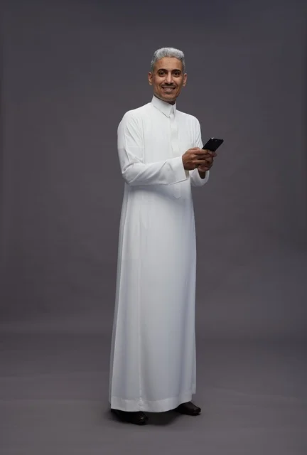 رجل سعودي بالثوب التقليدي يستخدم الهاتف الذكي