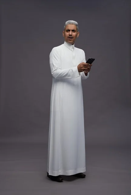 رجل سعودي بالزي التقليدي يحمل هاتف ذكي