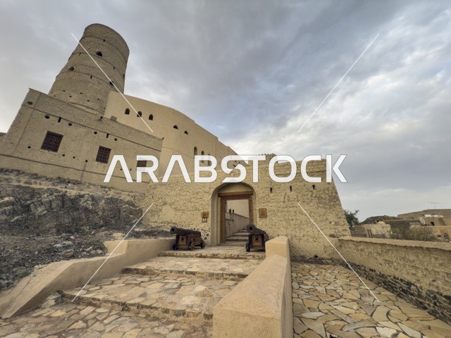 Bahla Fort in Oman showcasing its historic mud architecture and defensive towers under a dramatic cloudy sky. bahla.Oman  .