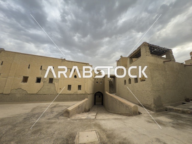 منظر لقلعة بهلا التاريخية في سلطنة عمان يظهر العمارة الطينية العريقة وأبراجها الدفاعية تحت سماء غائمة