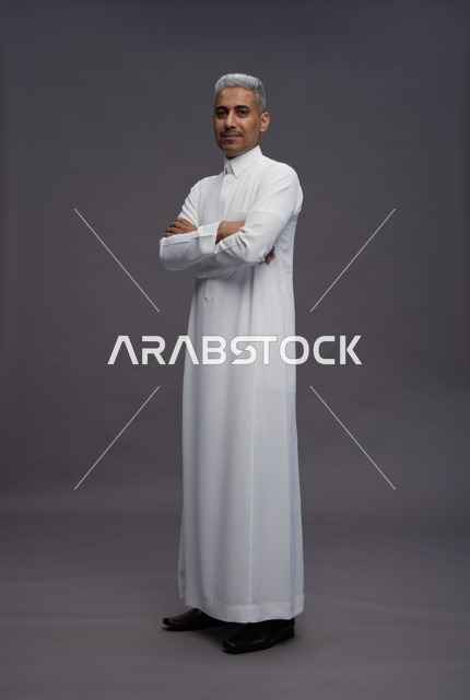 رجل سعودي بالثوب الأبيض واضعاً ذراعيه فوق بعضهما