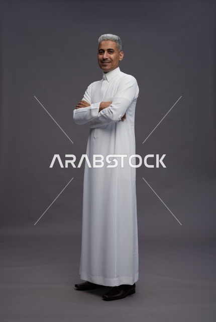 رجل سعودي يرتدي الثوب الأبيض يقف بوضعية واثقة في الاستوديو