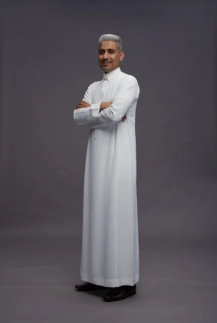 رجل سعودي يرتدي الثوب الأبيض يقف بوضعية واثقة في الاستوديو