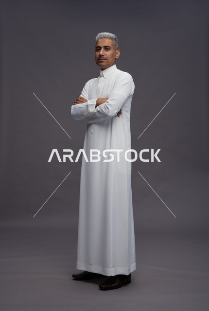 رجل سعودي بالثوب الأبيض يقف مكتوف اليدين