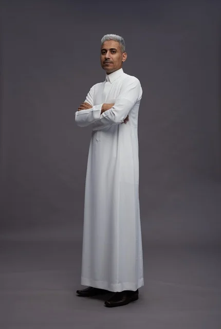 رجل سعودي بالثوب الأبيض يقف مكتوف اليدين