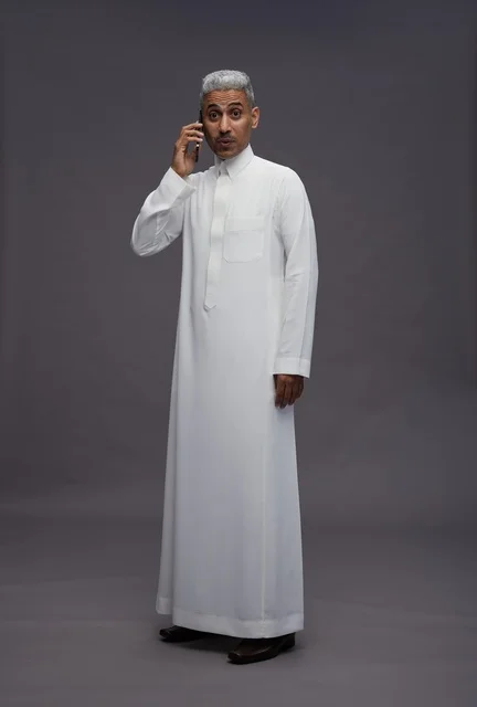 Saudi man in white thobe talking on a smartphone
