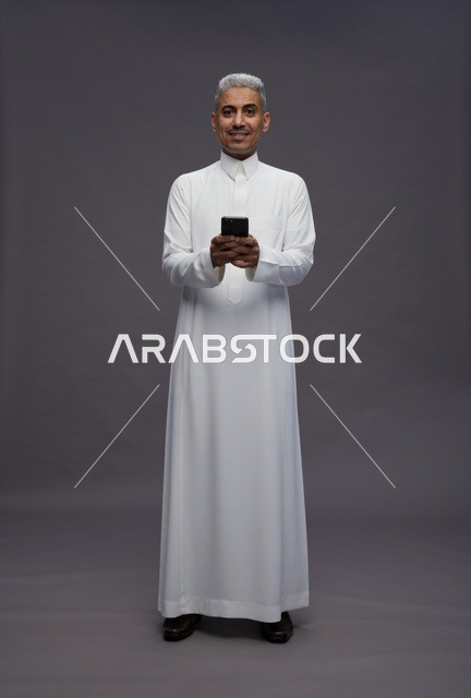 رجل سعودي يستخدم هاتفًا ذكيًا بالزي التقليدي