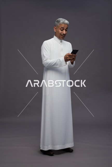 رجل سعودي بالزي التقليدي يستخدم هاتف ذكي
