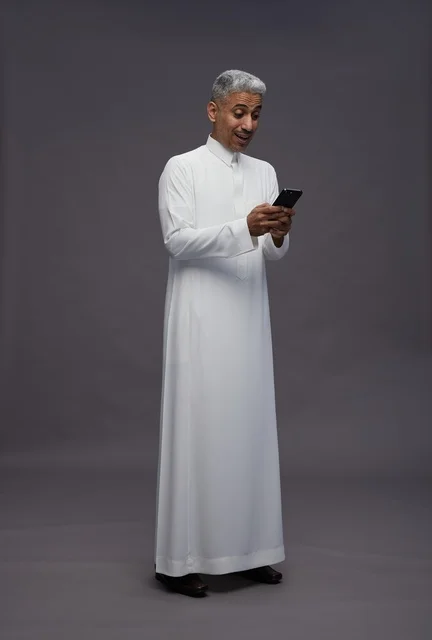 رجل سعودي بالزي التقليدي يستخدم هاتف ذكي