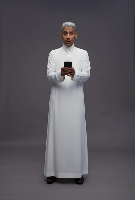 رجل سعودي بالثوب التقليدي يمسك هاتف ذكي
