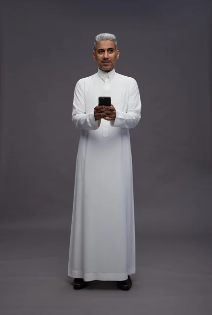 رجل سعودي بالزي التقليدي يستخدم الهاتف الذكي