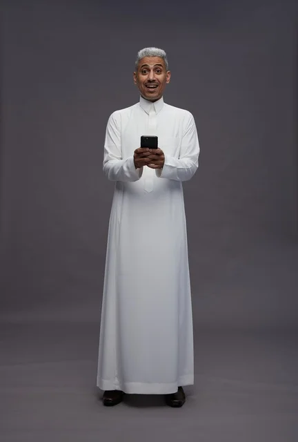 رجل سعودي بالزي التقليدي يستخدم هاتفاً ذكياً