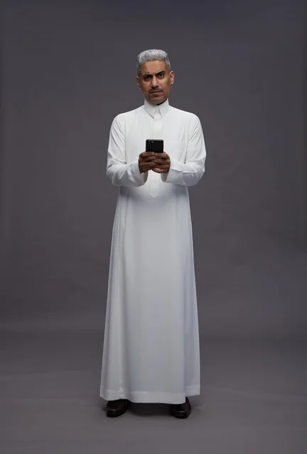 رجل سعودي بالزي التقليدي يستخدم الهاتف الذكي