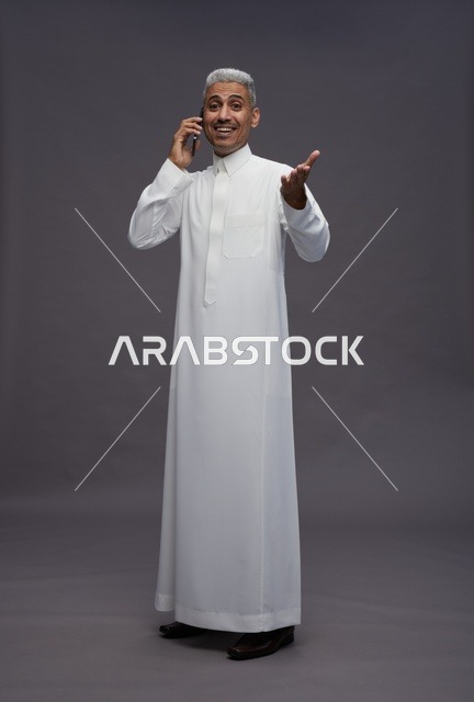 رجل سعودي بالثوب الأبيض يتحدث عبر الهاتف الجوال