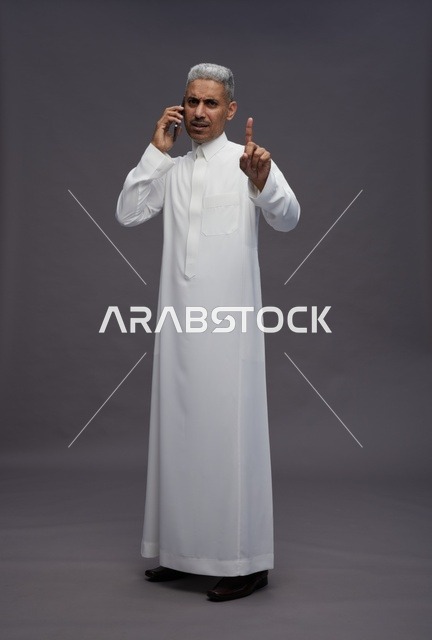 رجل سعودي بالثوب الأبيض يتحدث بالجوال