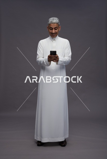 رجل سعودي بالزي التقليدي يستخدم الهاتف الذكي