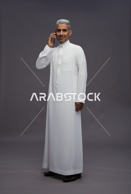 رجل سعودي بالثوب الأبيض يتحدث بالهاتف
