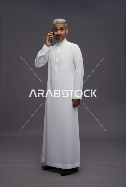 رجل سعودي بالثوب الأبيض يتحدث عبر الهاتف المحمول