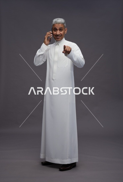 رجل سعودي بالثوب الأبيض يتحدث بالجوال ويشير للكاميرا