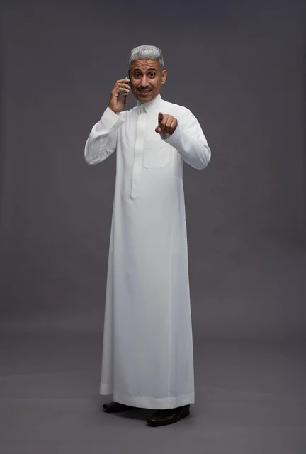 Saudi Man in White Thobe Talking on Smartphone Pointing