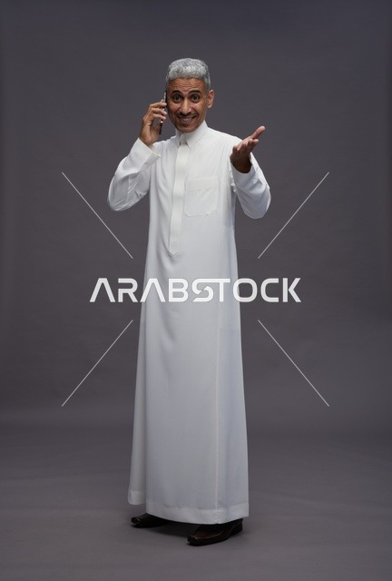 رجل سعودي يرتدي الثوب الأبيض يتحدث عبر الهاتف المحمول