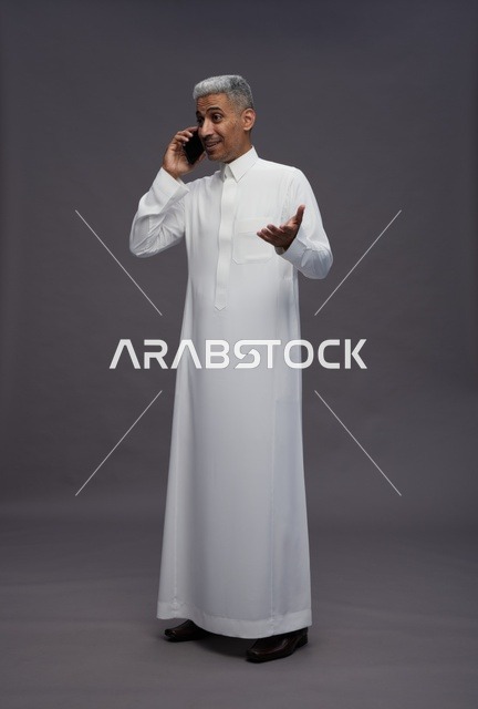 رجل سعودي بالثوب التقليدي يتحدث عبر الهاتف المحمول