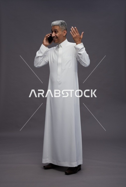 رجل سعودي بالثوب الأبيض يتحدث بالجوال في الاستوديو